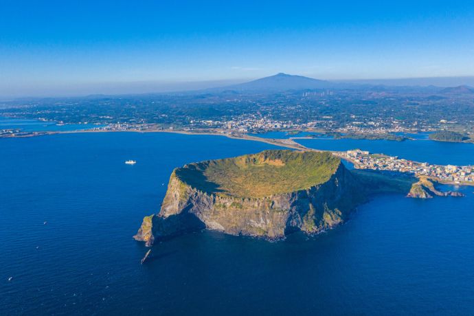 Aerial View of Seongsan Ilchulbong with Mt Hallasan in the background on Jeju Island